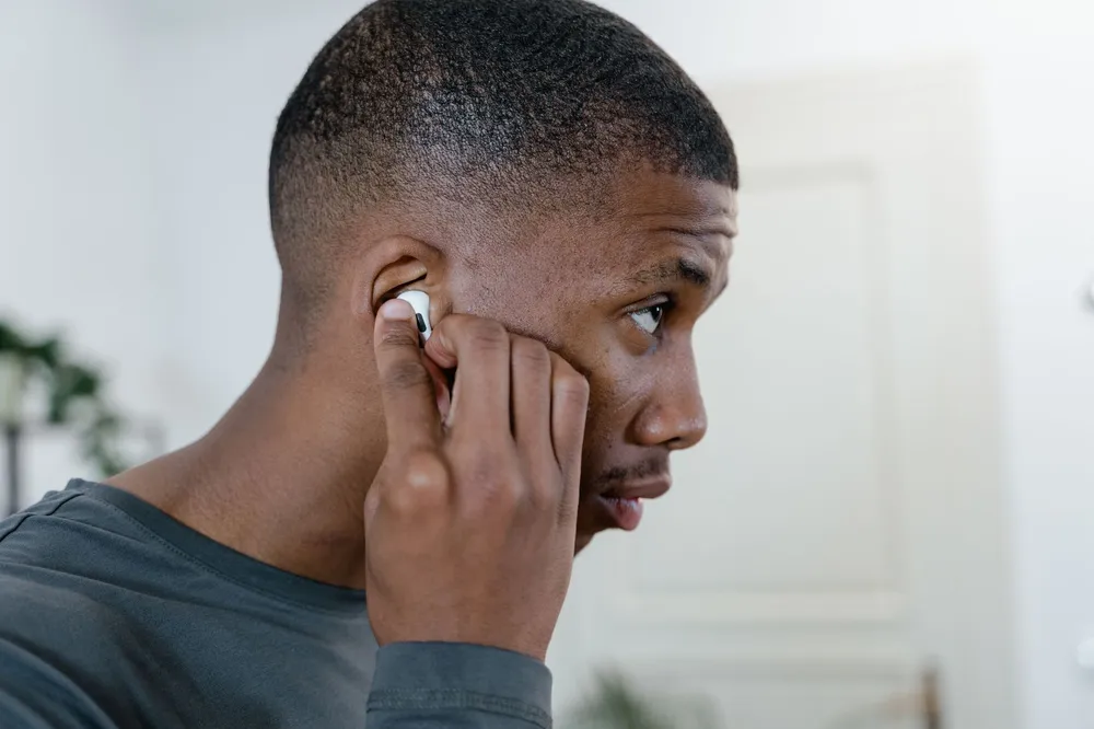 Personne insérant un écouteur sans fil dans son oreille